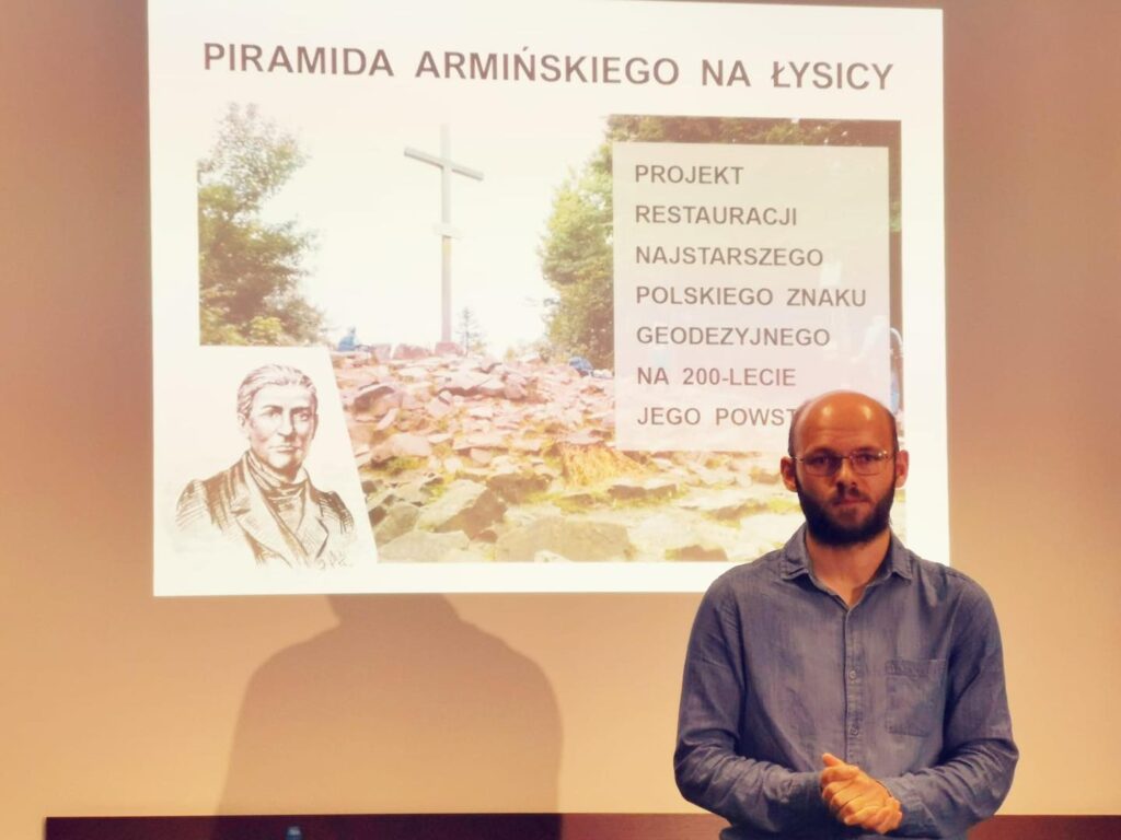 Prezentacja o "Piramidzie Armińskiego na Łysicy". Kluczowe obiekty: portret, krzyż, tekst. Kontekst: geodezja, historia.