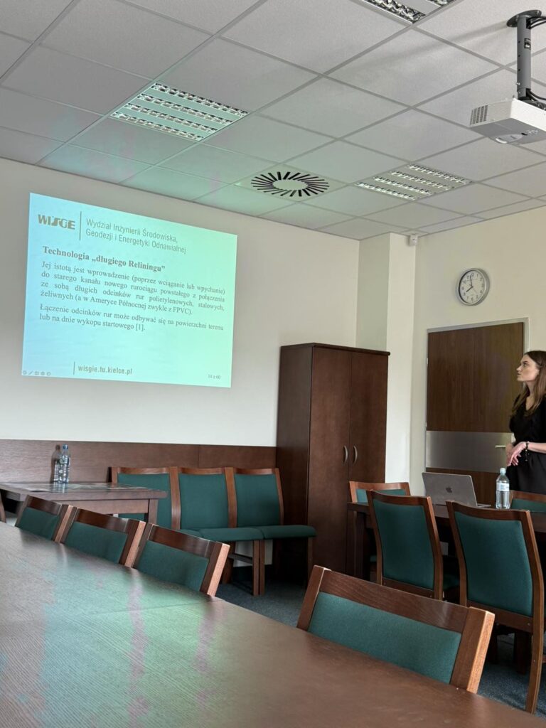 Prezentacja o technologii "długiego reliningu" na Wydziale Inżynierii Środowiska. Widoczne krzesła, stoły, projektor, ekran.