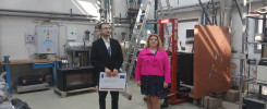 Mężczyzna i kobieta stoją w laboratorium. W tle widoczne są rury, drabina i sprzęt badawczy.