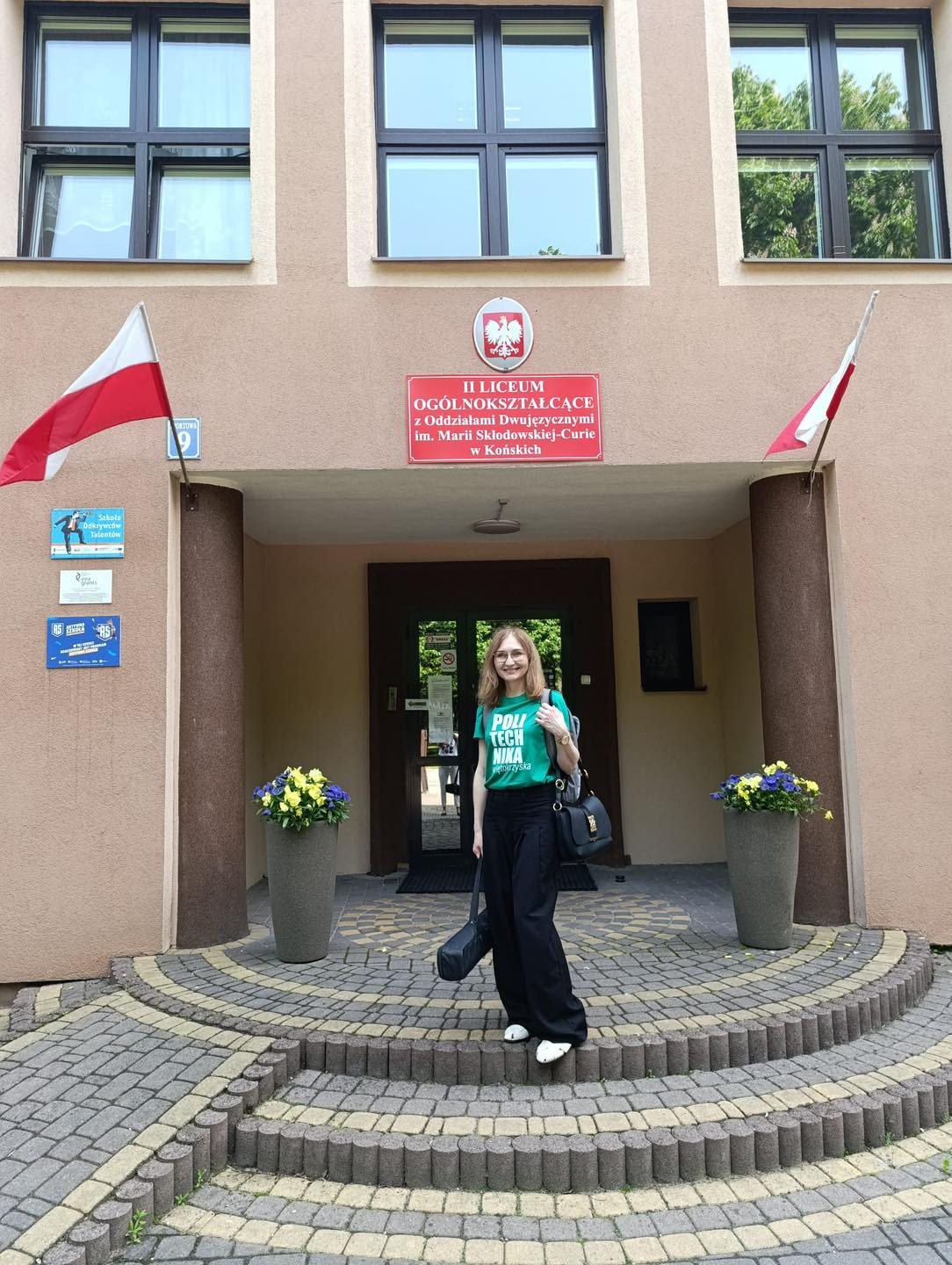 Kobieta przed budynkiem II Liceum Ogólnokształcącego z Oddziałami Dwujęzycznymi im. Marii Skłodowskiej-Curie w Końskich.