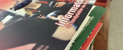 Stos informatorów "Informator dla kandydatów na studia". Kluczowe obiekty: informatory, stół, laptopy.