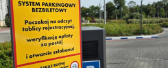 Znak informuje o systemie parkingowym bezbiletowym. Kluczowe obiekty: znak STOP, kasa parkingowa, szlaban.