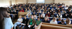 Wykład w auli uniwersyteckiej. Studenci siedzą w rzędach, słuchając wykładowcy.