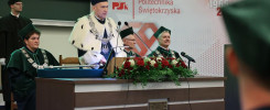 Uroczystość na Politechnice Świętokrzyskiej. Kluczowe obiekty: osoby w togach, kwiaty, podium.