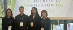 Cztery osoby stoją przed banerem konferencji "Studencka Konferencja Pasjonatów GIS" w Hotelu HP Park w Olsztynie.